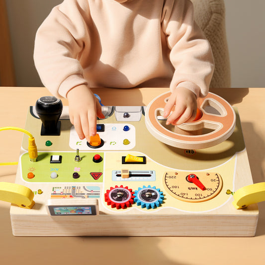 A toddler playing with a wooden steering wheel busy board, featuring realistic buttons, gears, and colorful letters on the back.